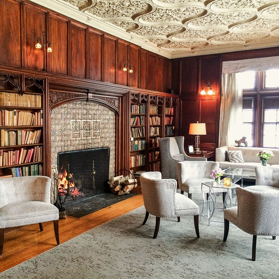 The Castle's Library featuring a large fireplace, reading chairs, and large bookshelves 