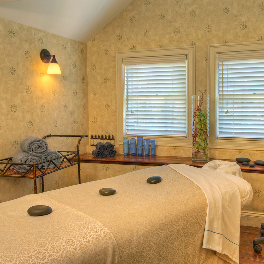 The inside of a spa room with a massage table, hot stones, and towels surrounding the table